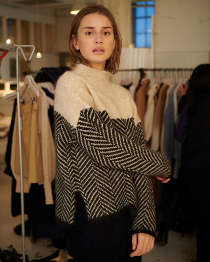 A woman wearing a zigzag-pattern funnel neck jumper styled elegantly for an autumn day out.