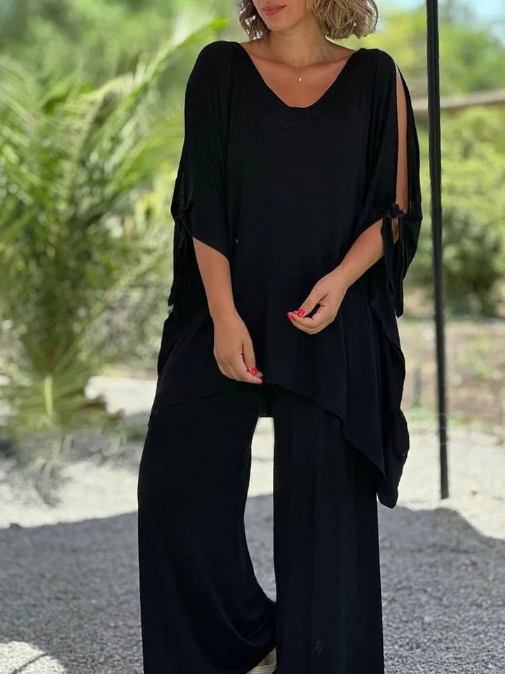 A woman wearing a draped top with shoulder cut-out details and matching wide trousers.