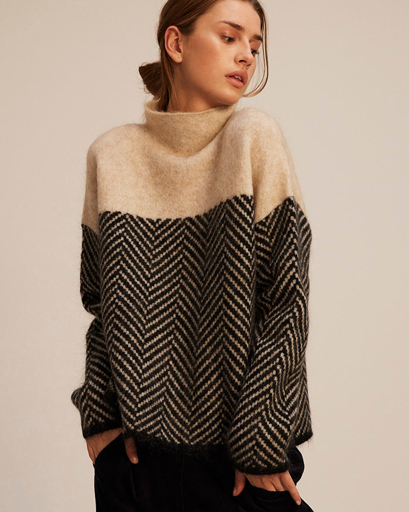 A woman wearing a zigzag-pattern funnel neck jumper styled elegantly for an autumn day out.