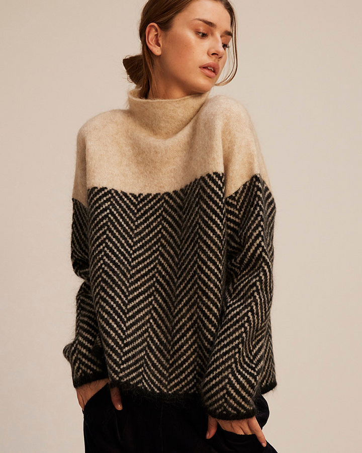 A woman wearing a zigzag-pattern funnel neck jumper styled elegantly for an autumn day out.