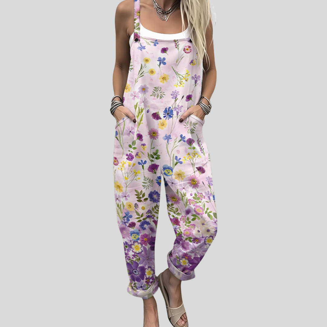 Women's relaxed wide-leg dungarees in soft blush pink with a fine scattered wildflower print in pink, yellow, blue and violet.