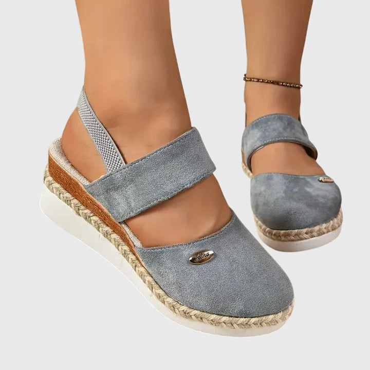 Black closed-toe wedge espadrilles with a wide stretch strap and a braided-trim platform wedge.