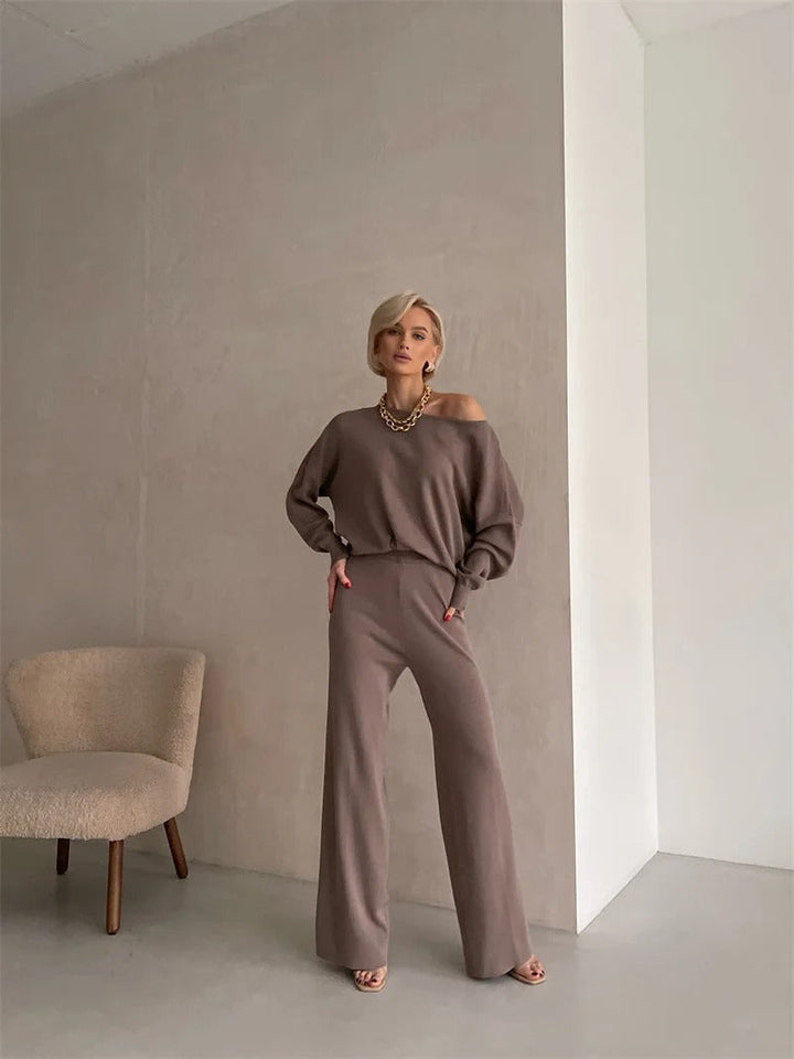 A woman wearing an off-shoulder draped top with wide-leg trousers