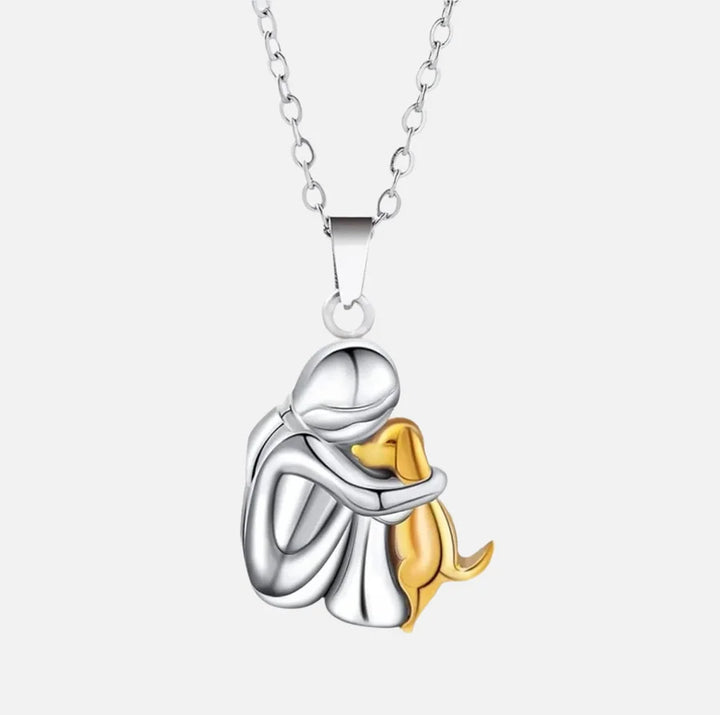 Gold pendant necklace showing a person and dog in a tender embrace