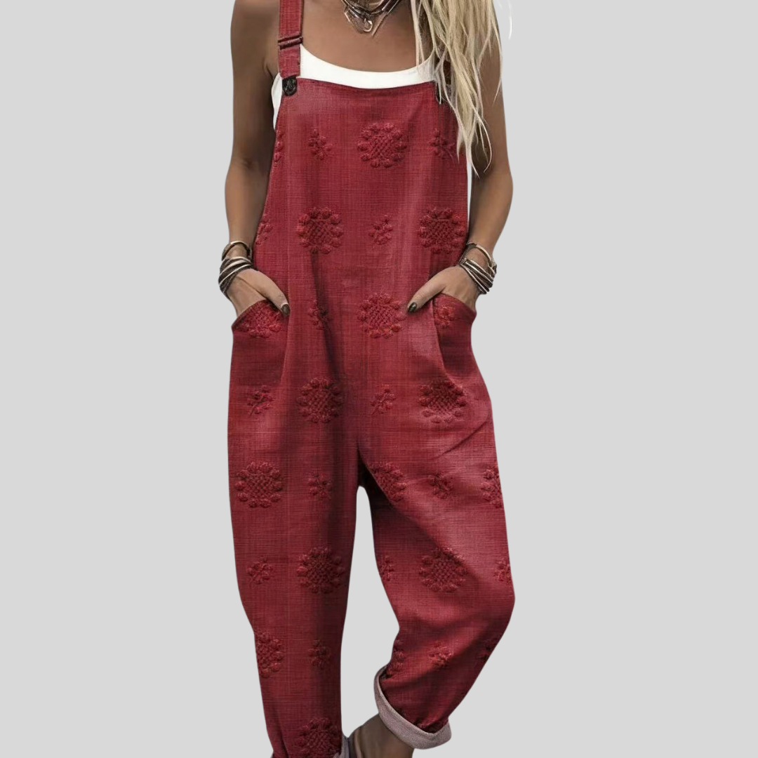 Woman wearing the Aisling™ warm brick-red harem-leg dungarees with a delicate tone-on-tone woven floral and star motif across the fabric.