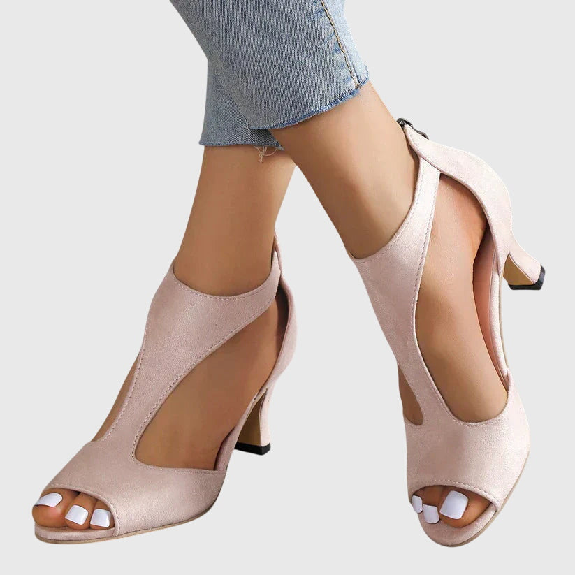 A woman wearing flexible orthopaedic heels, standing comfortably in a polished everyday outfit.