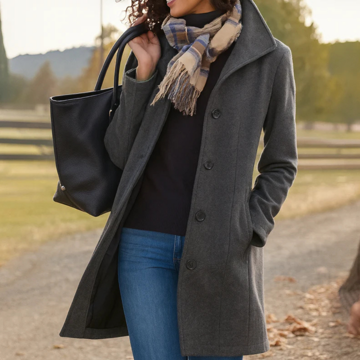 A woman wearing an elegant single-button coat over a jumper on a crisp autumn day.