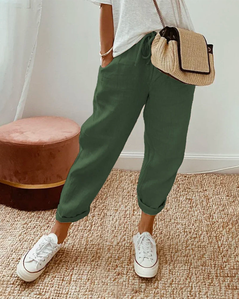 A woman wearing flowing elegant trousers with a soft elastic waist and deep pockets.