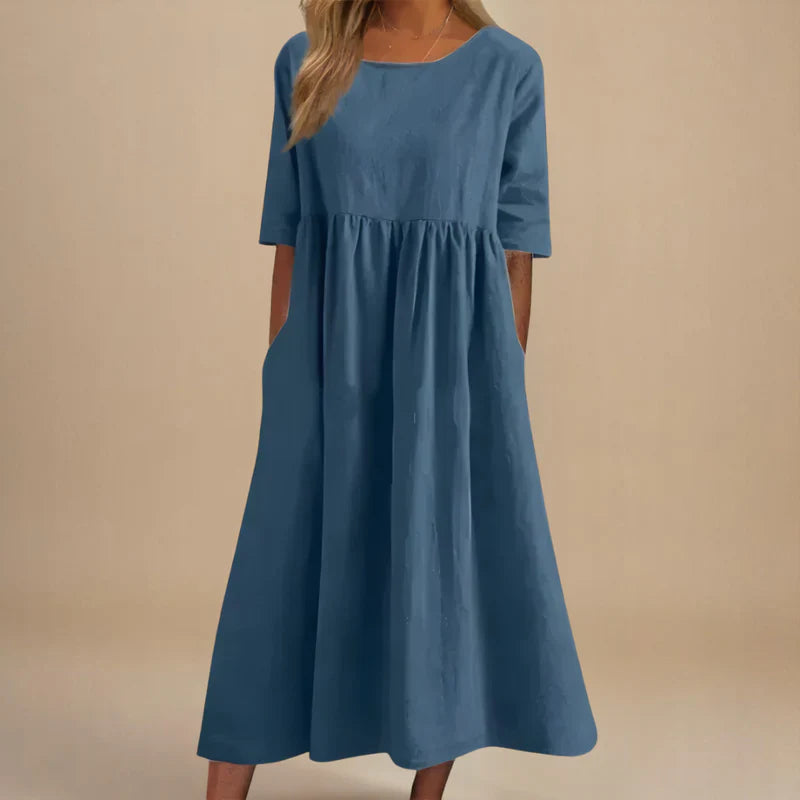 A woman wearing the Carmel flowing day dress with a gathered waist and elbow-length sleeves.