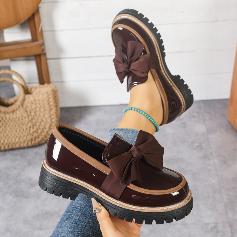 Green and black glossy loafers with a bold bow detail at the front