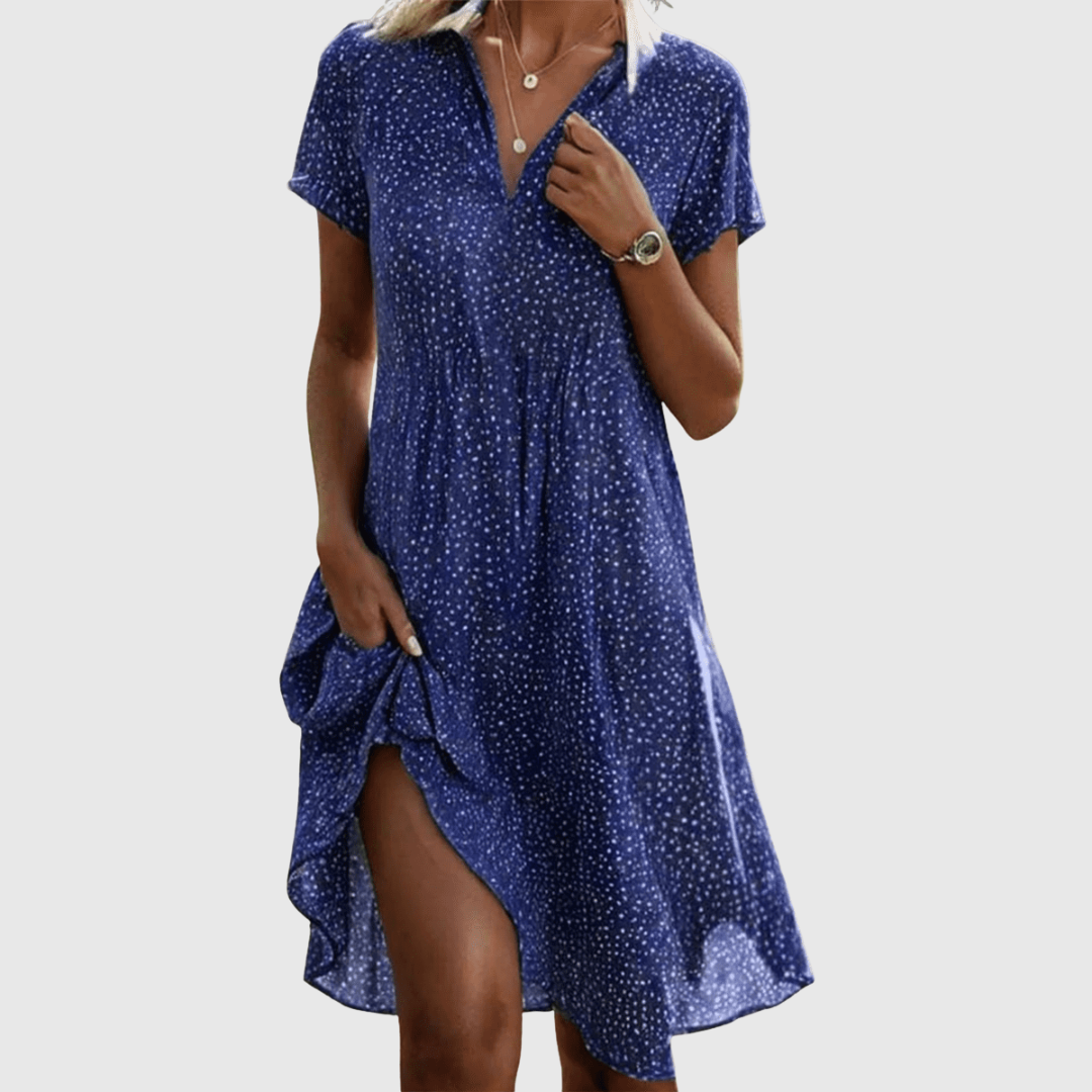 Woman wearing the Amy speckled summer dress in green, smiling in the sunshine outdoors.