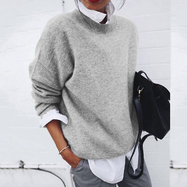 A woman wearing a soft mustard round-neck jumper with an elegant modern shape, relaxed and warm.