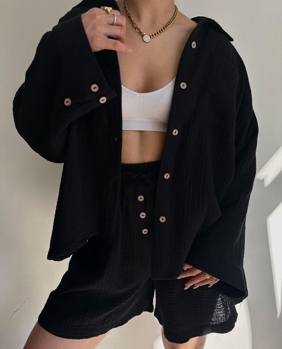 A woman wearing a flowing oversized shirt with drawstring shorts, relaxed and breezy.