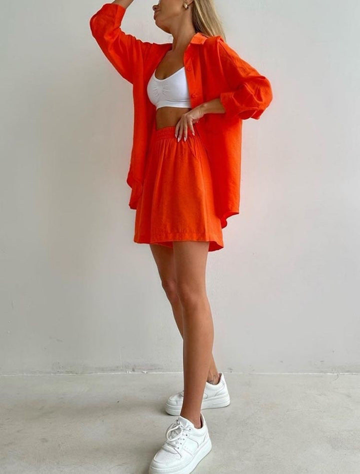 A woman wearing an oversized button-up shirt with matching high-waisted shorts.
