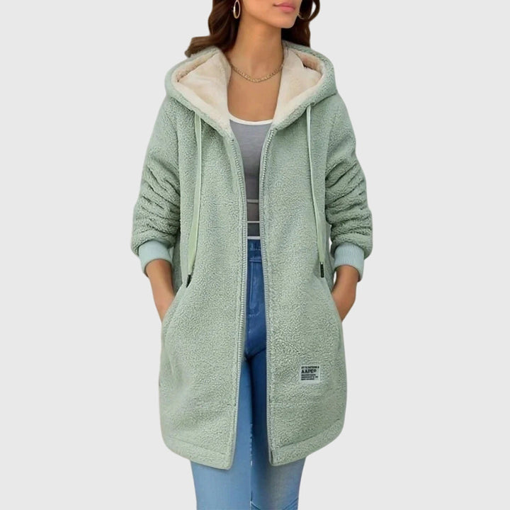 A woman wearing a cosy hooded jacket wrapped up warm on a cold winter morning.