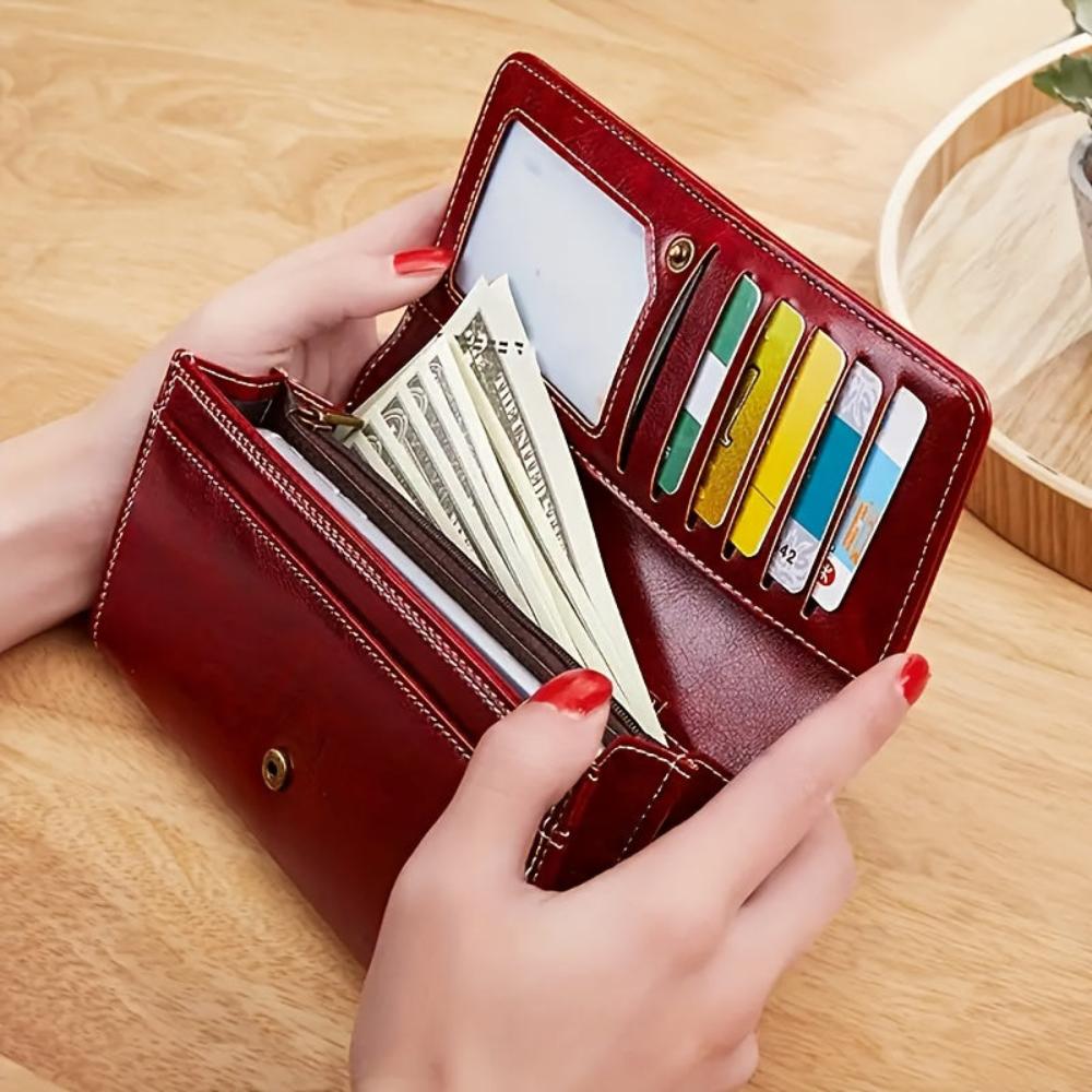 A woman holding an open bifold wallet, tucking a card into its slot.