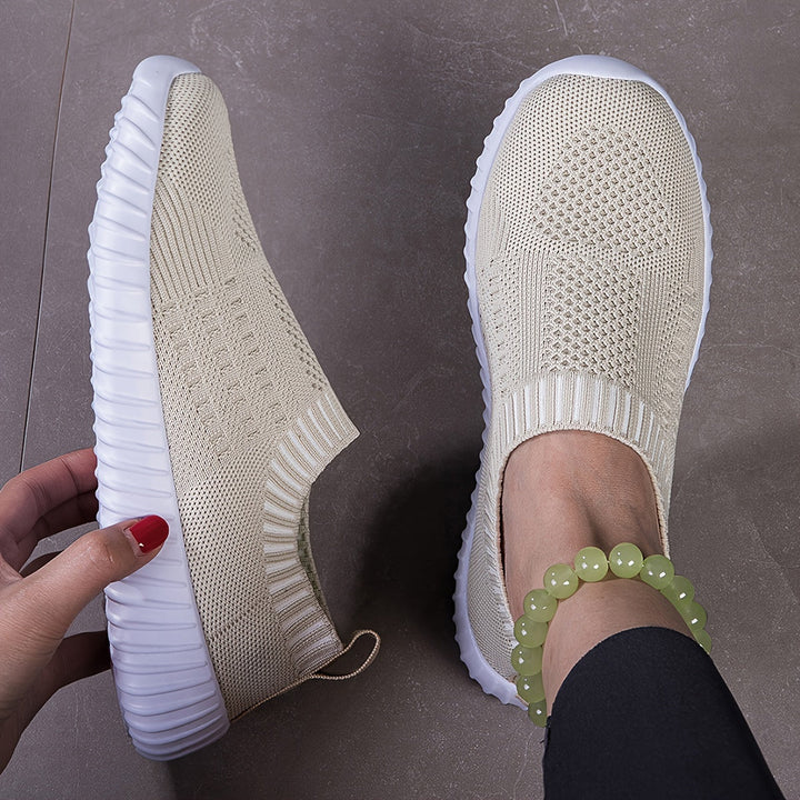 A woman slipping on ultralight sock-style trainers that hug the foot.