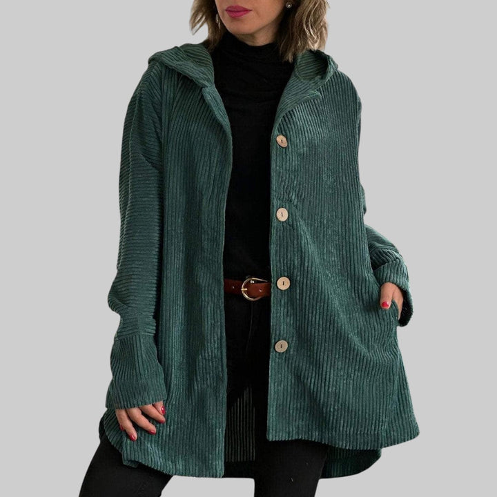 A woman wearing a hooded textured jacket outdoors in autumn