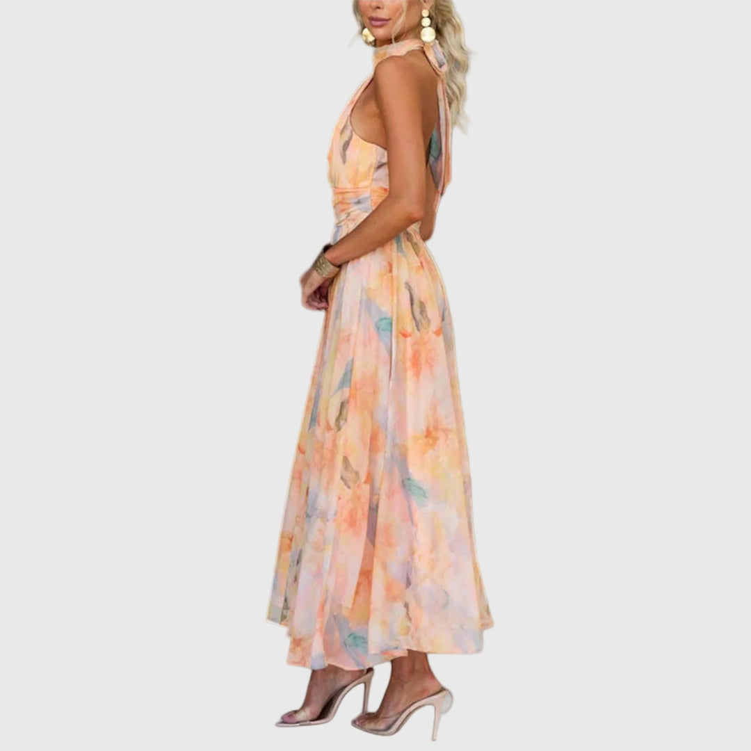 Woman wearing the Rachel halterneck maxi dress in warm watercolour tones at an outdoor celebration.