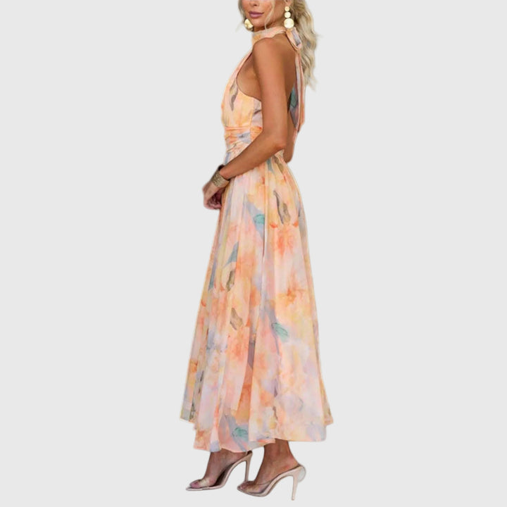 Woman wearing the Rachel halterneck maxi dress in warm watercolour tones at an outdoor celebration.