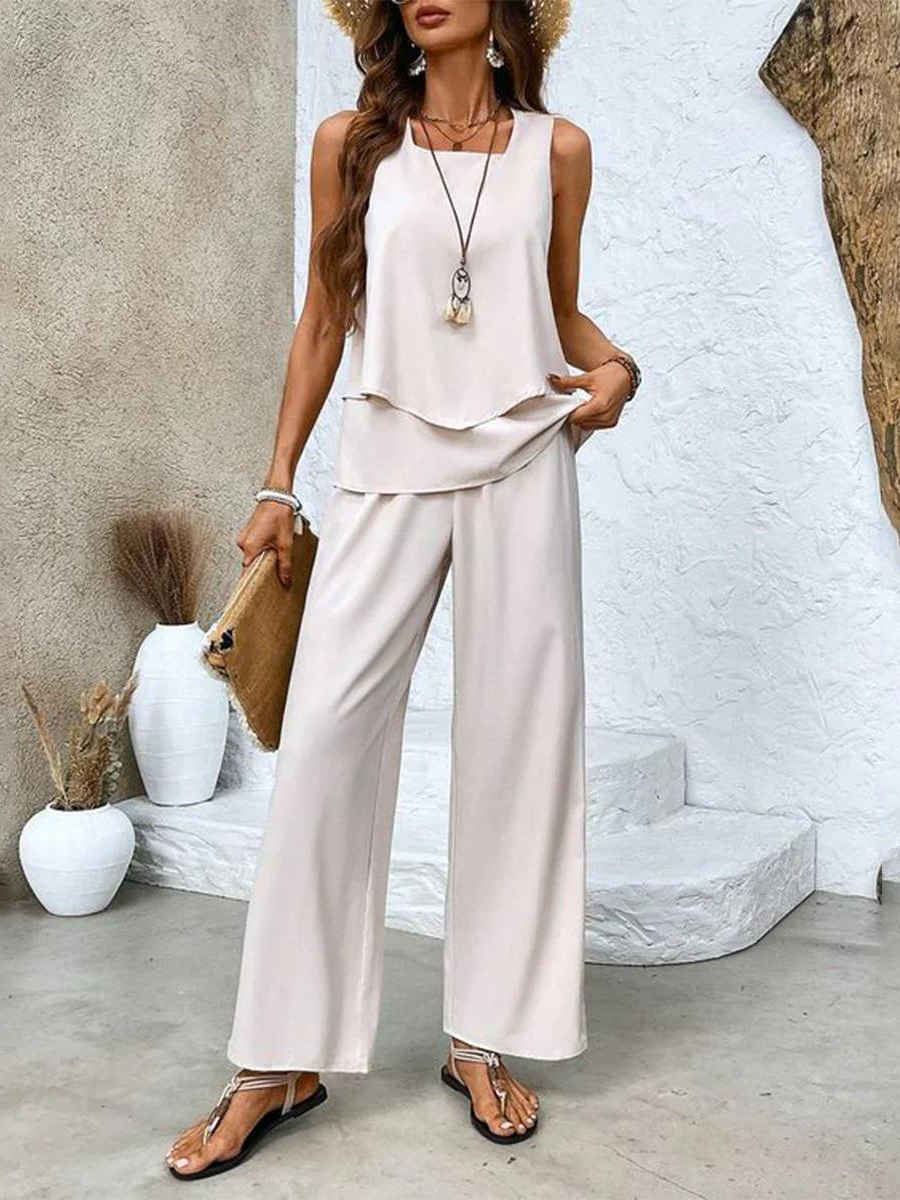 A woman wearing a layered sleeveless top with leaf-print wide-leg trousers, light and elegant.