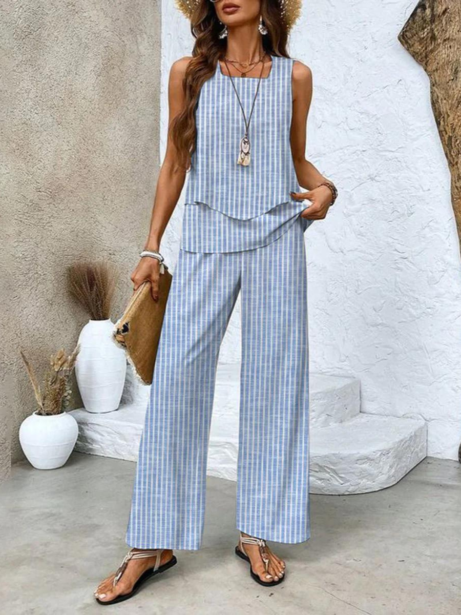 A woman wearing a layered sleeveless top with leaf-print wide-leg trousers, light and elegant.