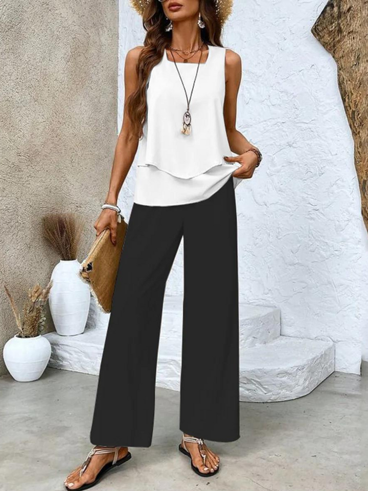 A woman wearing a layered sleeveless top with leaf-print wide-leg trousers, light and elegant.