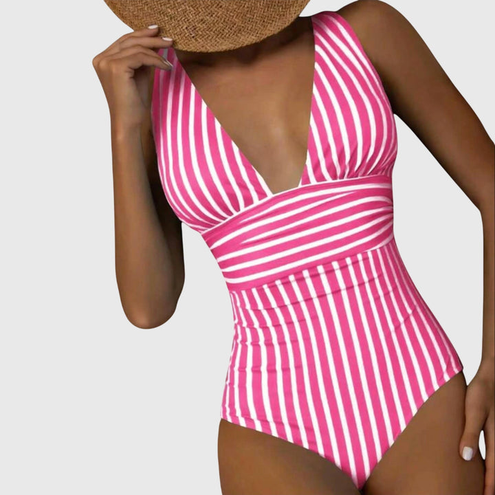 A woman walking by the sea in a bright printed swimsuit, relaxed and glowing in the sun.