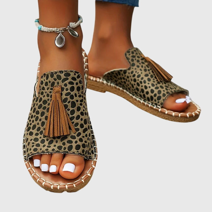 A woman wearing colourful patterned boho slides with tassel details on a holiday day out.
