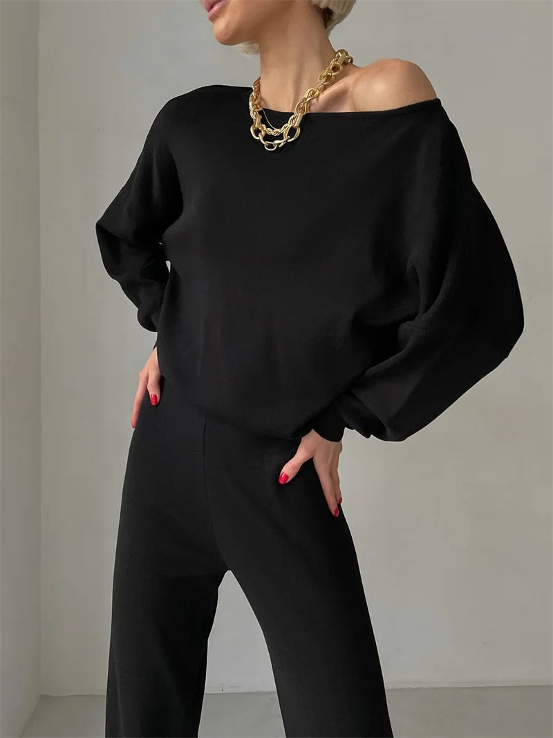 A woman wearing an off-shoulder draped top with wide-leg trousers