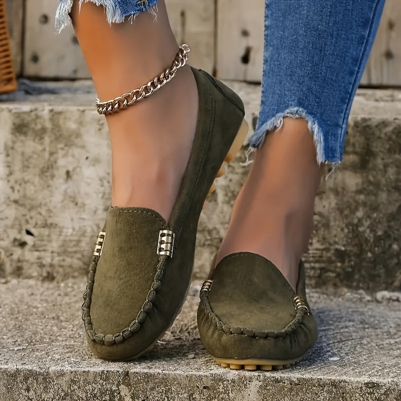 A woman in a ballet-flat loafer stepping lightly along a bright pavement.