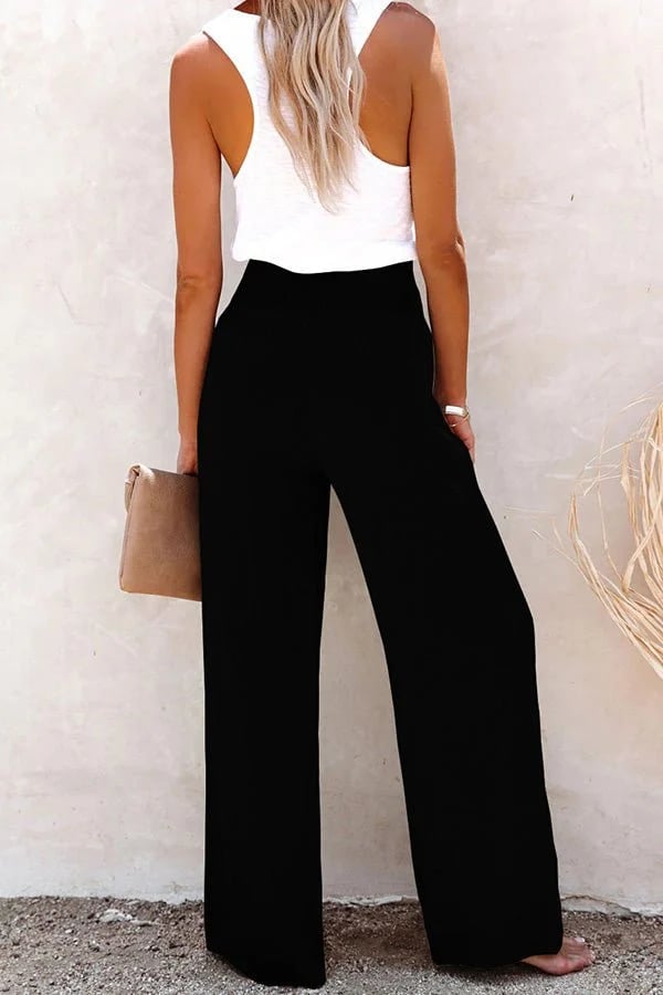 A woman in high-waisted loose wide-leg trousers with subtle button detailing, styled for an elegant everyday look.