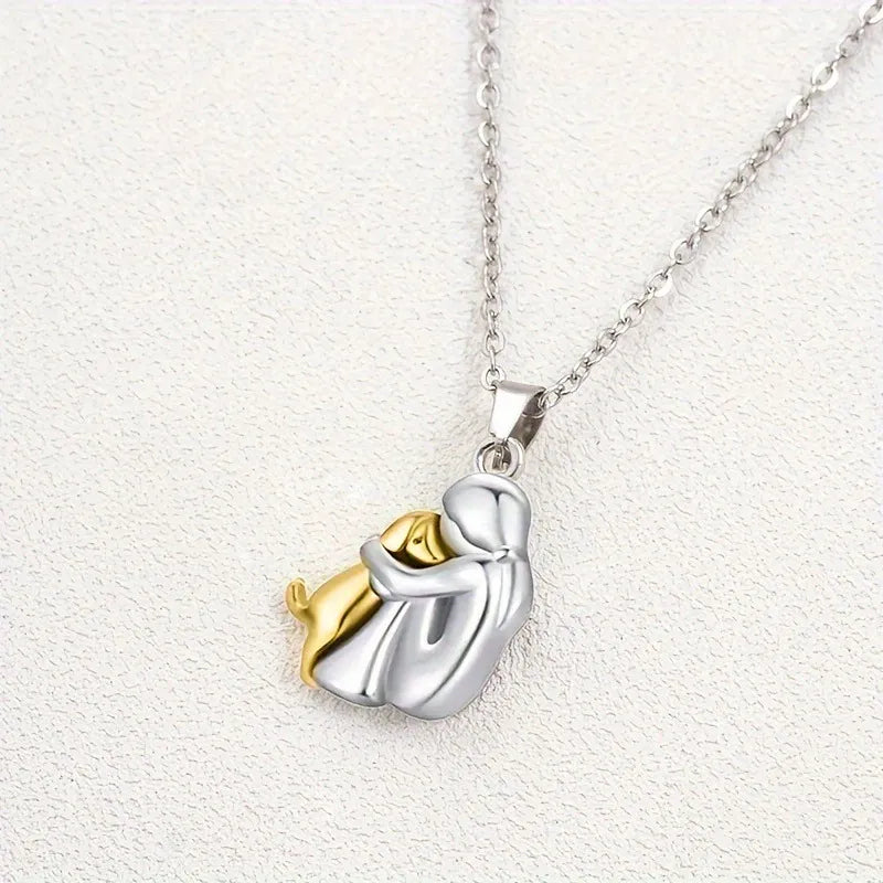 Gold pendant necklace showing a person and dog in a tender embrace