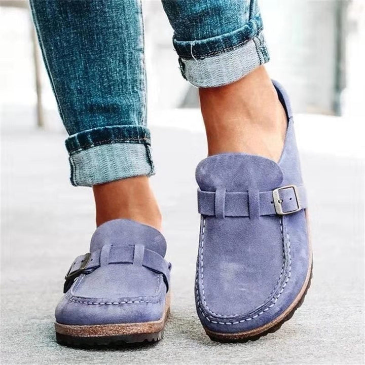 A woman wearing soft green bow loafers with cropped jeans on a city stroll.