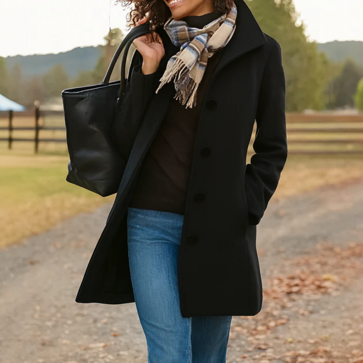 A woman wearing an elegant single-button coat over a jumper on a crisp autumn day.