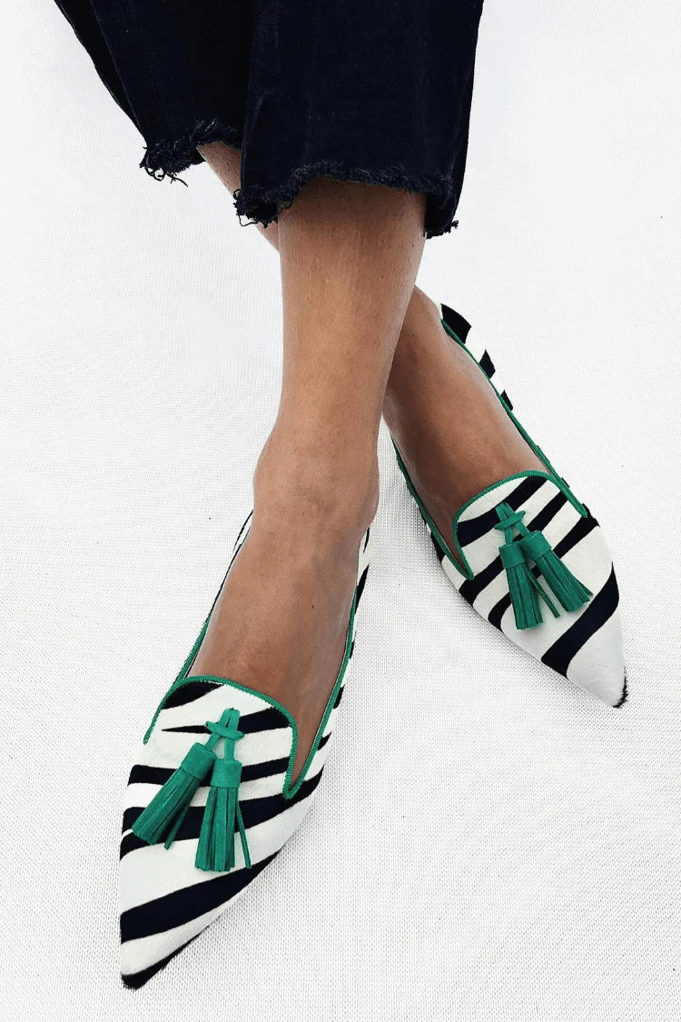 A woman wearing green zebra-print loafers with a simple, elegant outfit
