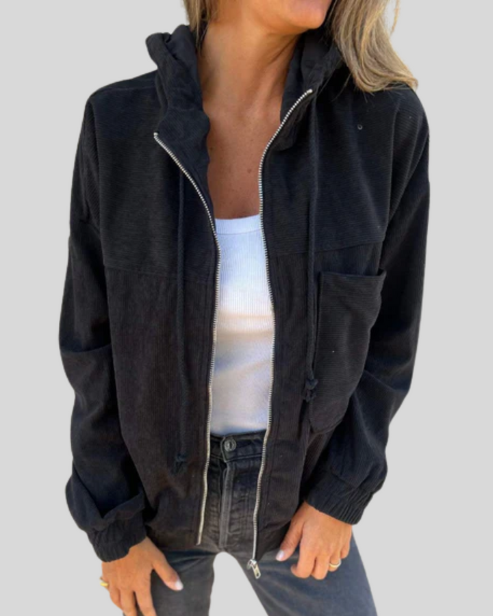 A woman wearing a zip-up hooded gilet with a soft ribbed texture, layered over a jumper.