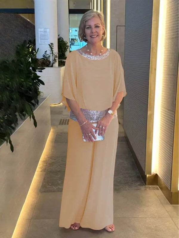 A woman wearing an embellished blouse-style top with softly flowing wide evening trousers.