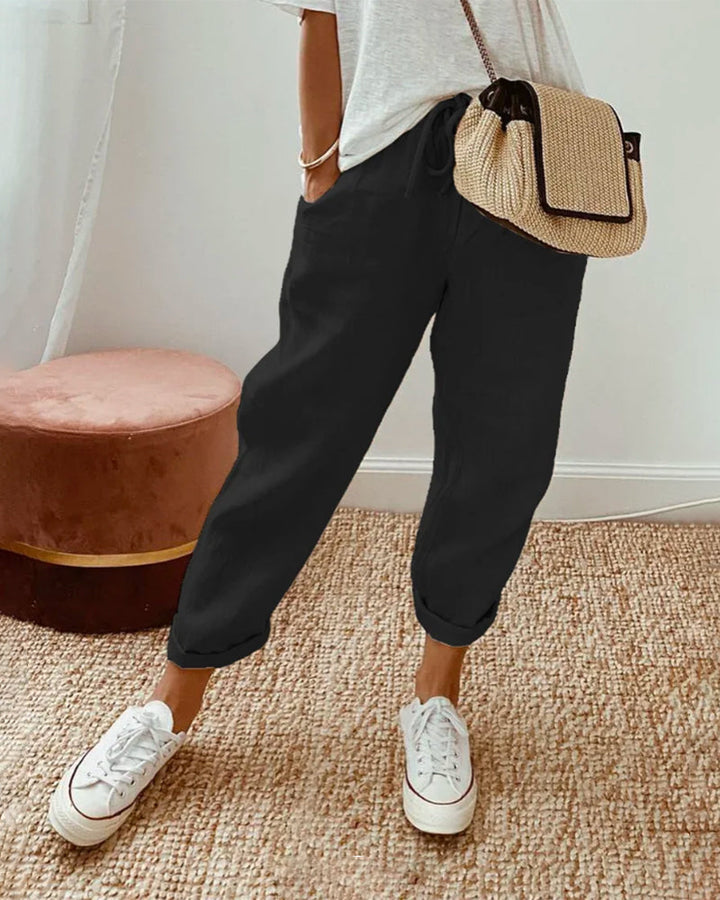 A woman wearing flowing elegant trousers with a soft elastic waist and deep pockets.