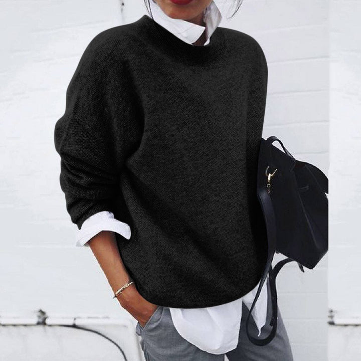 A woman wearing a soft mustard round-neck jumper with an elegant modern shape, relaxed and warm.