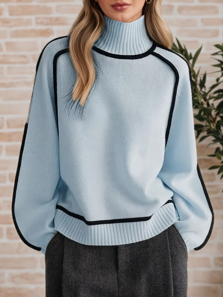 A woman wearing a funnel neck jumper with contrast piping, styled with trousers for a smart-casual look.