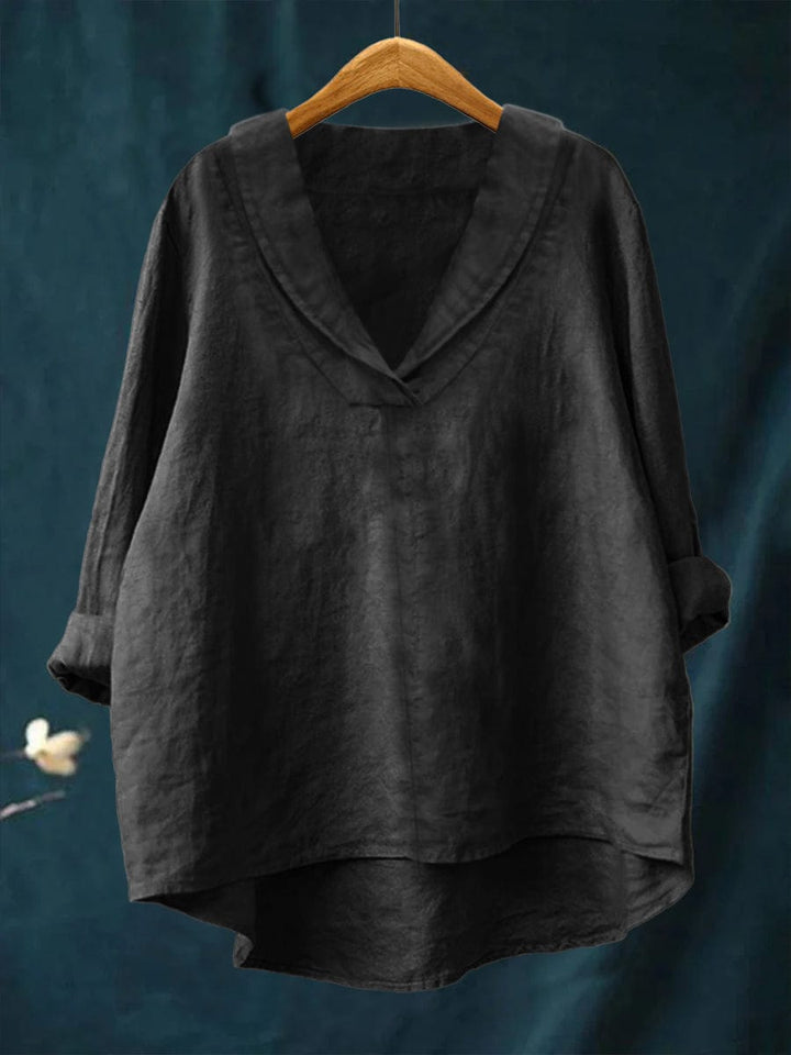 A woman wearing an elegant plain summer blouse with a flowing drape, styled with trousers.