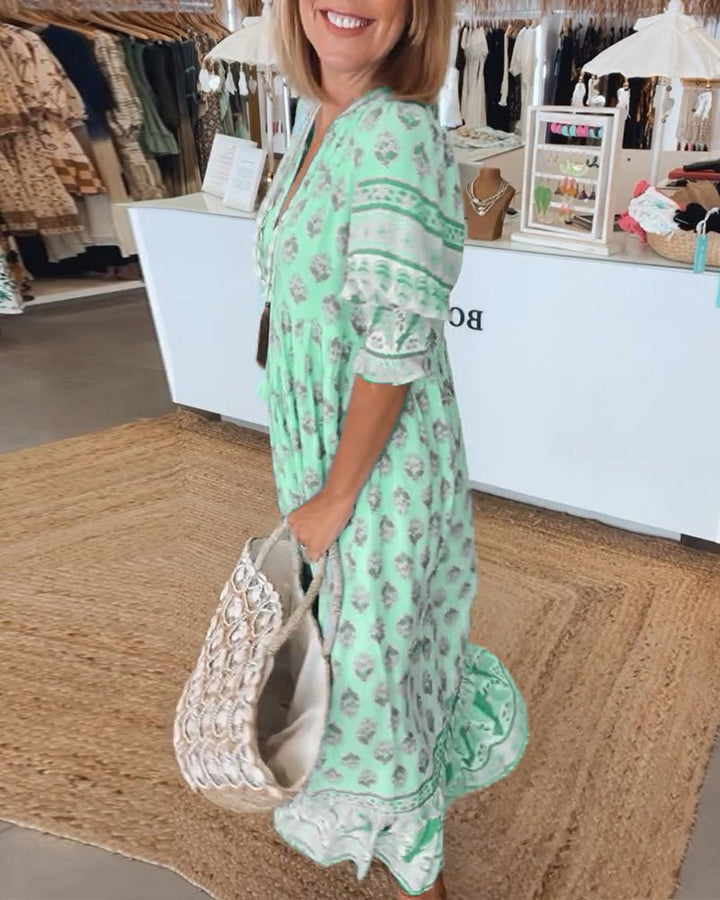 A woman wearing the Patricia boho floral midi dress with a fringed neckline and ruffled skirt.