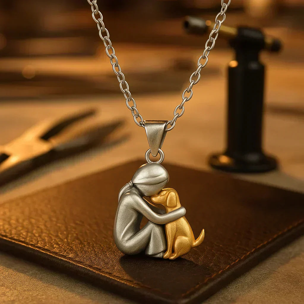 Gold pendant necklace showing a person and dog in a tender embrace