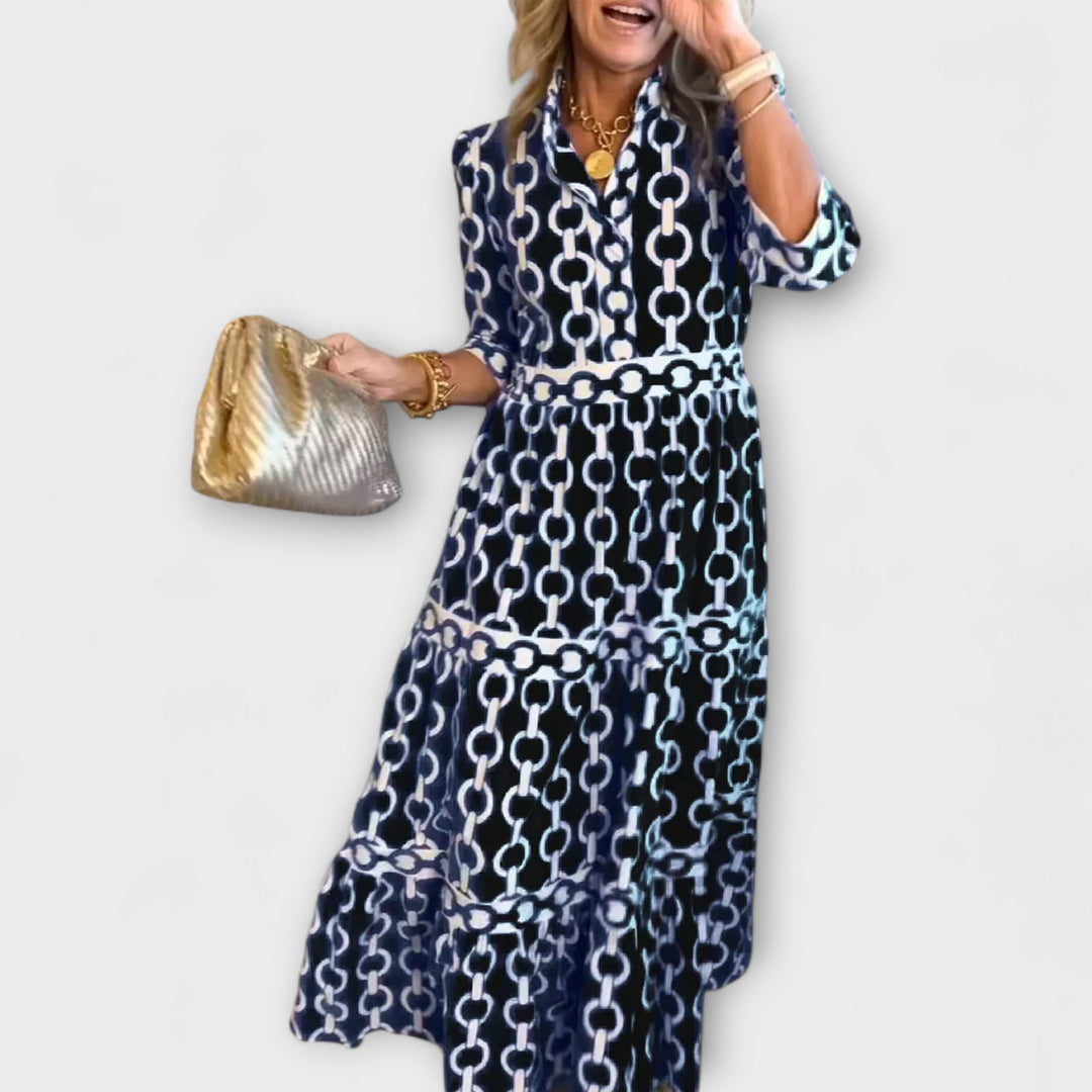 A woman wearing a flowing chain print midi dress that drapes elegantly as she walks.