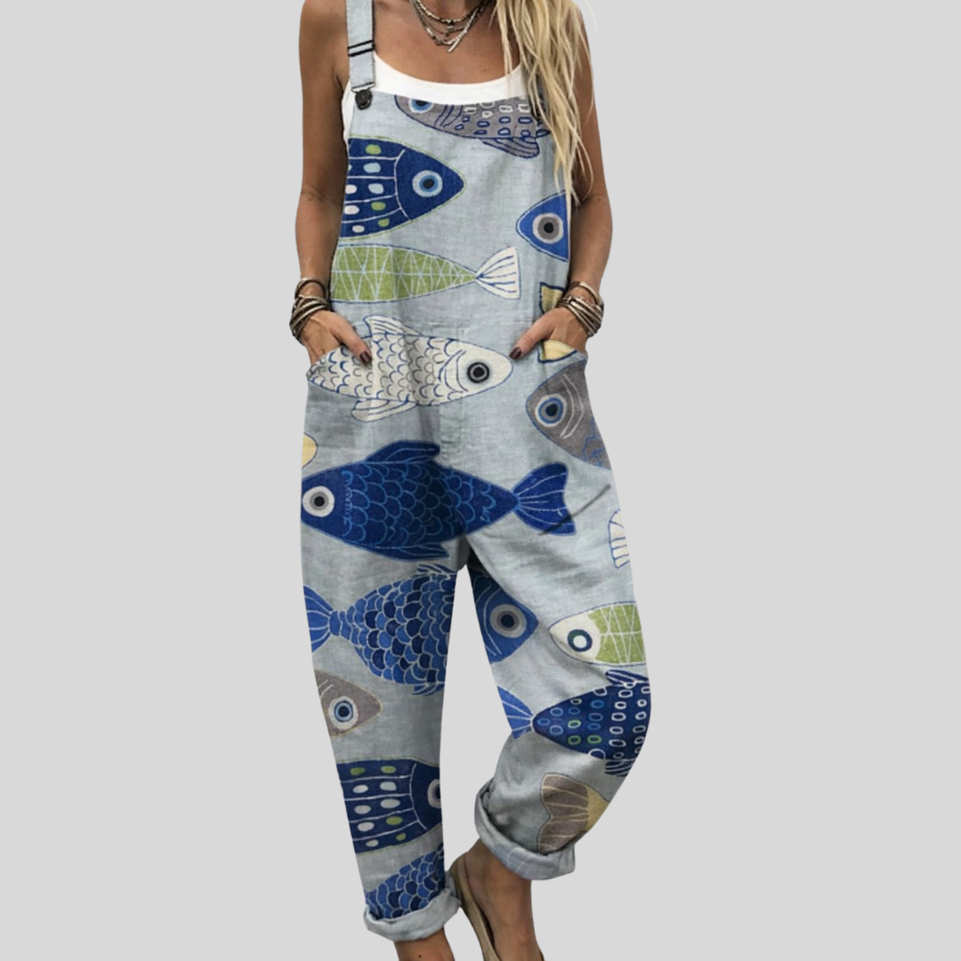 Light grey wide-leg dungarees with large bold stylised fish in blue and green, adjustable shoulder straps and side pockets.