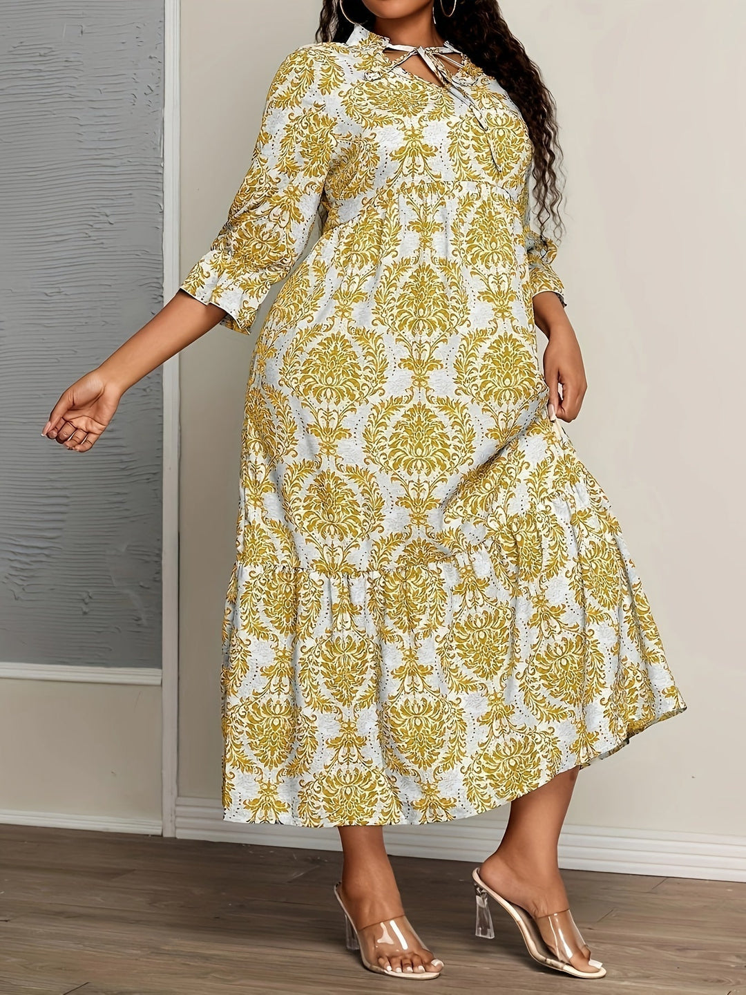Woman strolling by the sea in the Harriet mosaic print maxi dress with a keyhole neckline and bow detail.