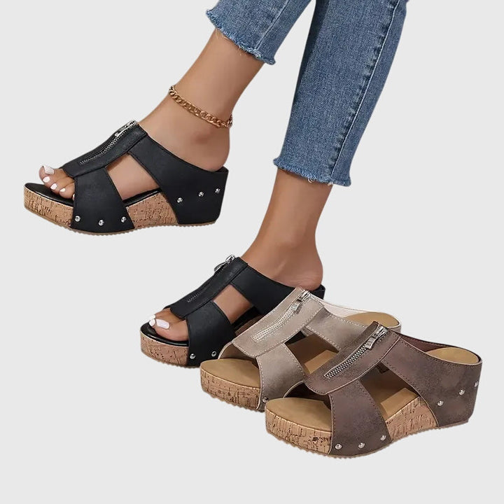 A woman standing comfortably in brown supportive sandals with an adjustable strap and cushioned sole.