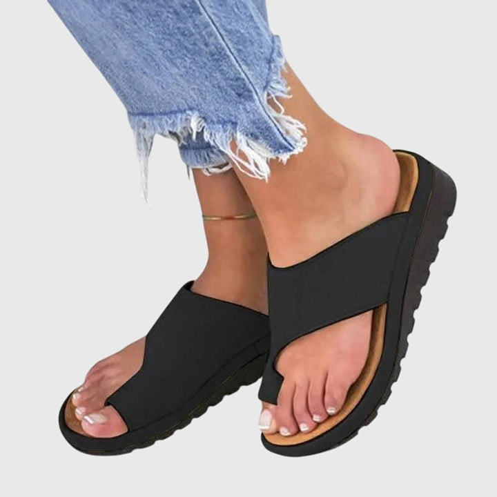 A woman in gold supportive sandals standing gracefully, feet cushioned and at ease.