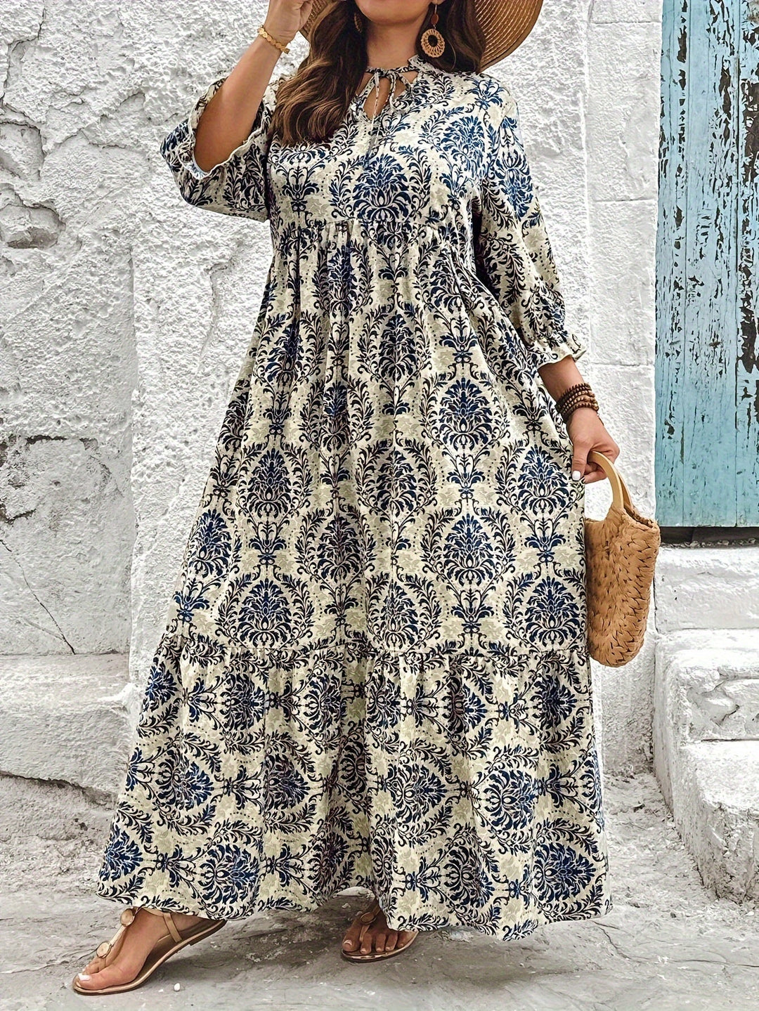 Woman strolling by the sea in the Harriet mosaic print maxi dress with a keyhole neckline and bow detail.
